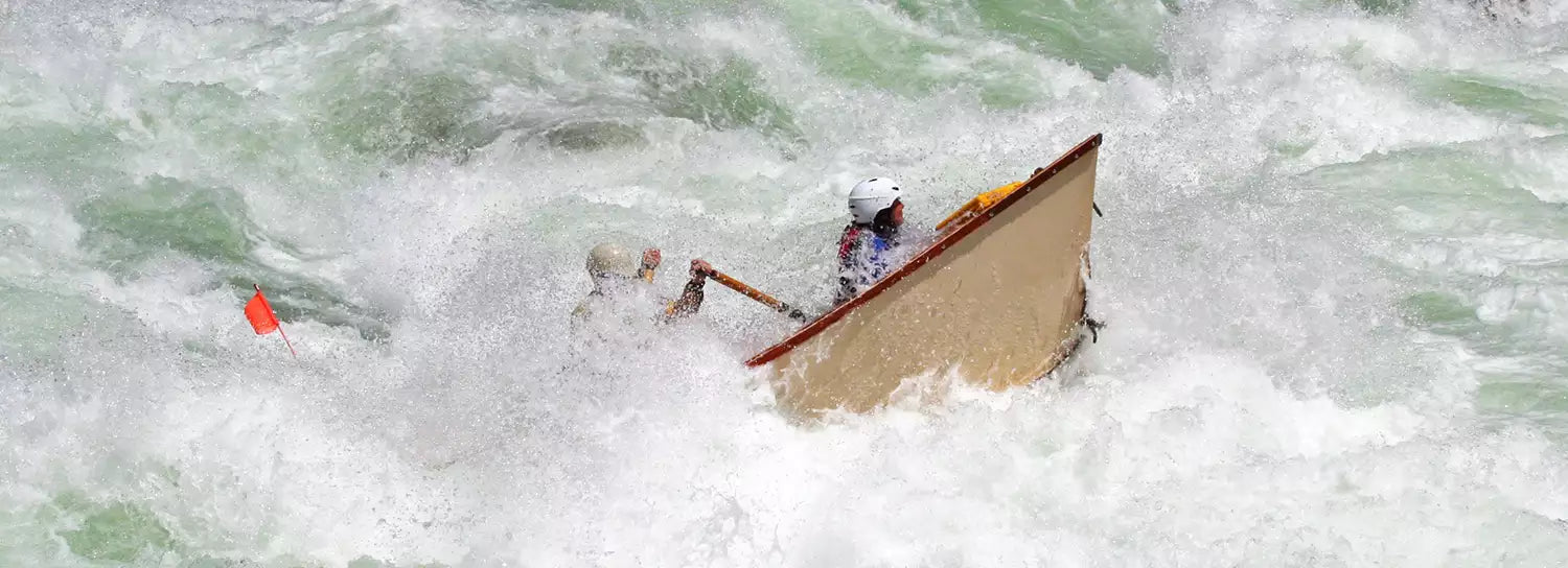 A man in a canoe is paddling through rapids.